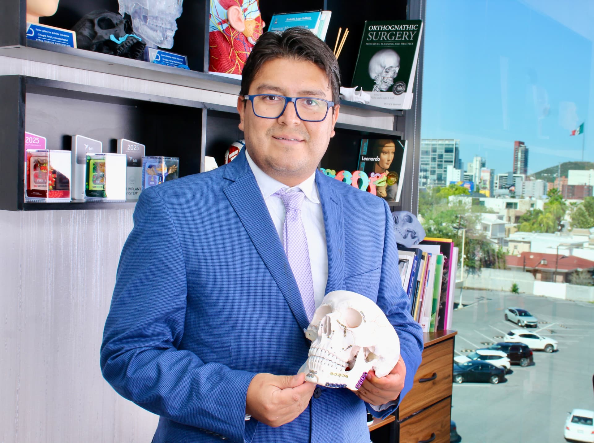 Dr. Juan Alberto Dávila con modelo anatómico craneofacial en su consultorio
