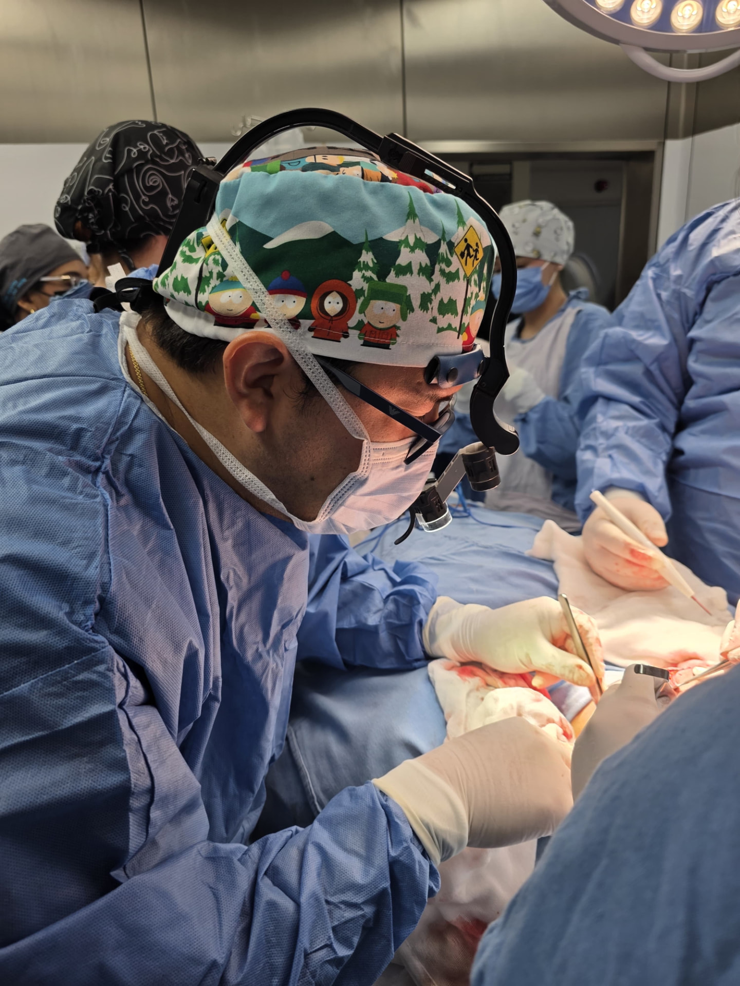 Dr. Juan Alberto Dávila operando con lupas quirúrgicas en quirófano